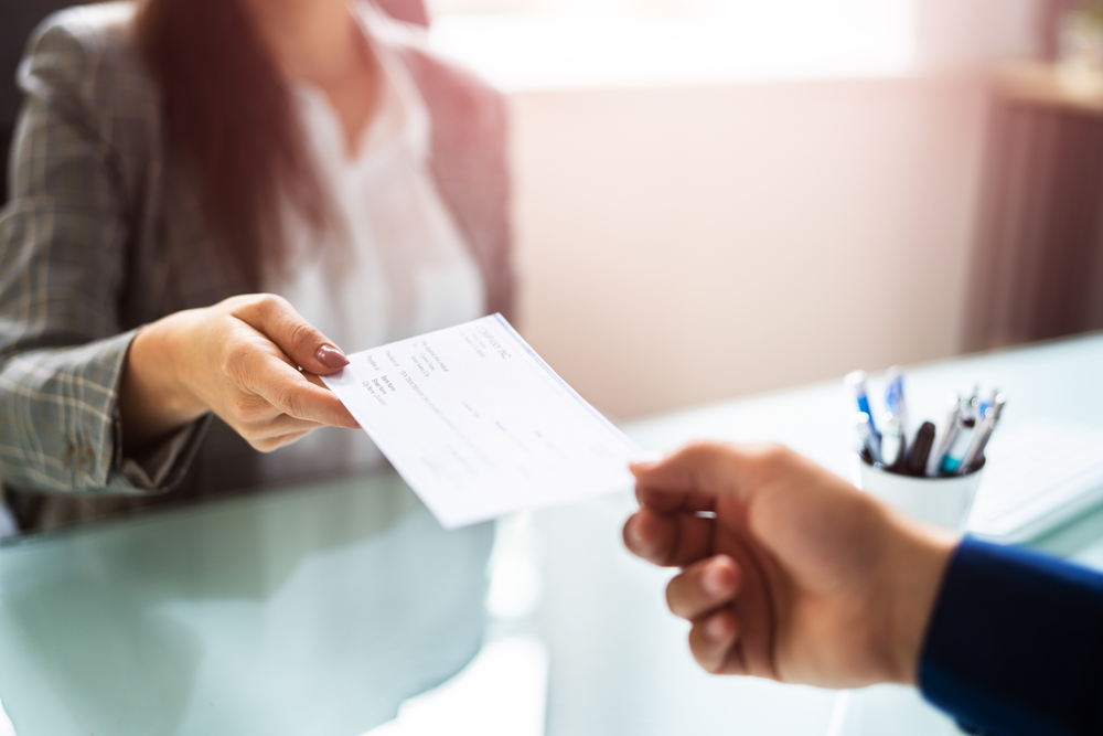 Woman Giving Cheque. Hand Holding Insurance Check